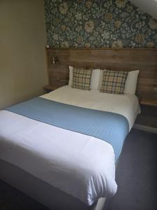 a bedroom with a large bed with white sheets and pillows at Rooms by the Oak in Baginton