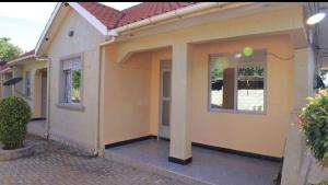 a yellow house with two windows on a street at Atié Haven in Lira