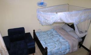 a bedroom with a canopy bed and a blue chair at Atié Haven in Lira +4 photos