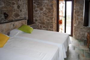1 dormitorio con 2 camas y pared de piedra en Casa Rural Romanejo, en Cabezabellosa