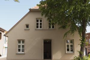 a white house with a door and a tree at JETHON Appartement am Wasserturm 2 in Nienburg