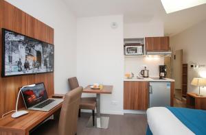 ein Hotelzimmer mit einem Schreibtisch und einem Laptop darauf in der Unterkunft Odalys City Metz Manufacture in Metz
