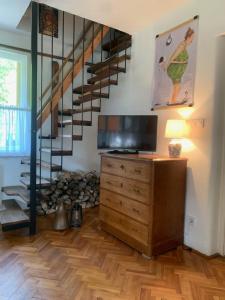 a living room with a wooden dresser and a spiral staircase at Tūlevél/Pine-needles in Tata +16 photos
