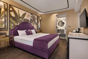 ein Schlafzimmer mit einem lila Bett und einem Gemälde an der Wand in der Unterkunft The New Hotel Zeybek in Izmir + 67 Fotos