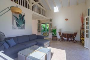 a living room with a blue couch and a table at Villa Providencia jacuzzi 1 min plage Le Diamant in Le Diamant
