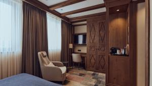 a room with a bed and a chair and a television at Grey Family Hotel in Kopaonik