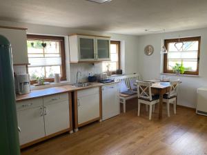 a kitchen with white cabinets and a table with chairs at Haus Dekostüble in Münstertal