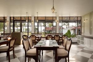 a dining room with tables and chairs and windows at Sanskreti in Cochin