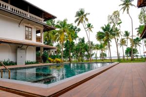 a swimming pool in front of a house with palm trees at Sanskreti in Cochin