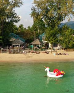 a plastic unicorn boat in the water near a beach at Tiki Beach Koh Phangan Beach Restaurant Bar and Coworking in Ban Tai +87 photos