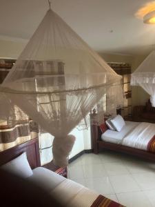 a bedroom with two beds and a mosquito net at Acactus Hotel in Kampala