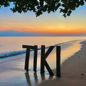 a wooden bench on the beach with the ocean at Tiki Beach Koh Phangan Beach Restaurant Bar and Coworking in Ban Tai
