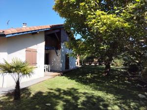 a house with a grass yard next to a building at Maison sous les arbres in Lit-et-Mixe