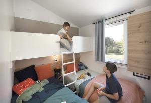 two children in a small room with a bunk bed at Camping Paradis Aloé in Médis