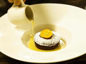 a white plate with a chocolate dessert with an orange on top at Giorgio e Flora Ristorante e Locanda in Arsiero