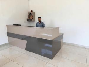 a man standing behind a counter in a white room at Sunburry Hotel Khatu 700mts from Temple in Khātu