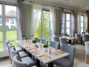 a dining room with tables and chairs and windows at Inselhotel Poel in Gollwitz