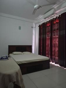 a bedroom with two beds and red curtains at Holiday Inn in Colombo +2 photos