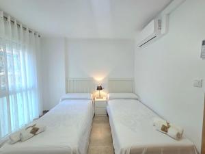 two twin beds in a room with a window at HomeHolidaysRentals Lorraine - Costa Barcelona in Malgrat de Mar +65 photos