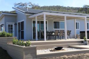 a house with a deck with a table and chairs at Tangory Farmstay in Glendon Brook