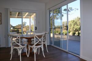 a dining room with a table and chairs and sliding glass doors at Tangory Farmstay in Glendon Brook