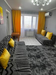 a living room with two couches and yellow pillows at Квартира 1 линия in Balqash
