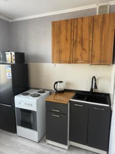a kitchen with a white stove and a refrigerator at Квартира 1 линия in Balqash