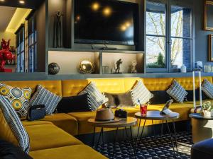 a living room with a yellow couch and a tv at ibis Styles Douai Gare Gayant Expo in Douai