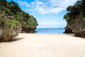 a beach between two cliffs with the ocean at Rich Reson Ishigaki in Ishigaki Island
