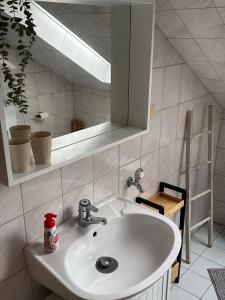 a bathroom with a white sink and a mirror at Gemütlich unterm Dach in Baunatal