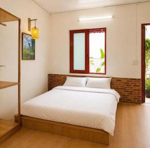a bedroom with a bed with a brick wall and a window at YARA - Stay & Coffee in Mỹ Ðuc
