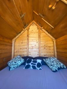 a bed in a wooden cabin with two pillows at Altaluna tiny house sotto le stelle in Trebbiantico