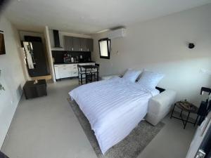 a bedroom with a white bed and a kitchen at Studio cosy avec terrasse in Montpellier