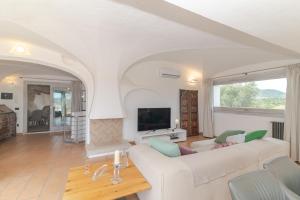 a living room with a white couch and a tv at Villa Roccia d'oro piscina privata in Porto San Paolo