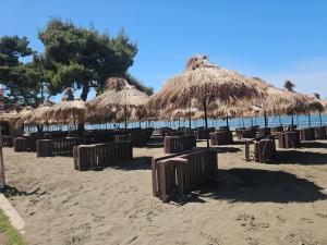 a beach with chairs and straw umbrellas and the ocean at Sea&Stay in Shëngjin