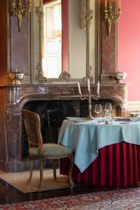a table with a chair in front of a fireplace at Château de Courcelles - Relais & Châteaux in Courcelles-sur-Vesle
