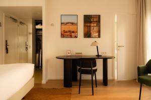 a bedroom with a table with a chair and a bed at 9Hotel Sablon in Brussels