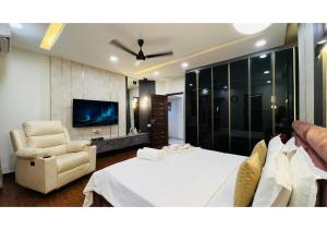 a bedroom with a bed and a chair and a tv at Olive Serviced Apartments - Central Delhi in New Delhi