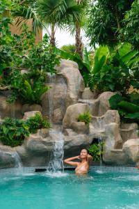 a man in a swimming pool with a waterfall at Chaykha Retreat Phuket in Chalong