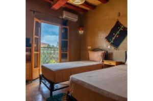 a bedroom with two beds and a window with a view at Gite Tamlli in Aoufous