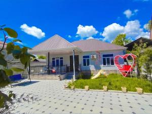 a house with a large red chair in the yard at Qəbələhouse in Gabala