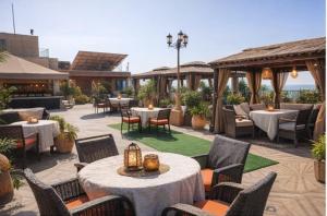 eine Außenterrasse mit Tischen und Stühlen und Tischsuche in der Unterkunft Devka Beach Resort in Daman
