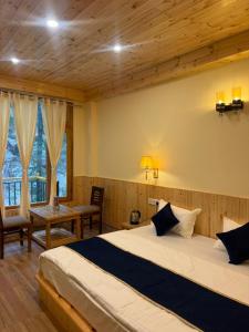 a bedroom with a bed and a table and a desk at The Zoland in Jibhi