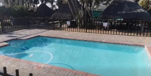 a large blue swimming pool next to a fence at Aurora Village in Polokwane