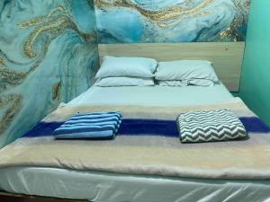 a bed with two pillows on it in front of a painting at Wind Stay in Male City