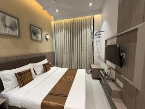 a hotel room with a large bed and a television at Hotel Unicorn Althan, Surat in Surat