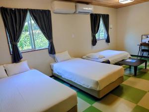 a bedroom with two beds and a table and windows at Rich Reson Ishigaki in Ishigaki Island +25 photos