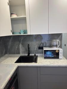a kitchen counter with a sink and a microwave at Квартира 2 комнаты in Balqash