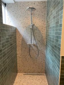a shower in a bathroom with a tiled wall at B&B huize Stoutenburght in Blesdijke