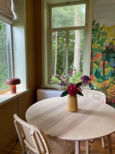 a dining room table with a vase of flowers on it at B&B huize Stoutenburght in Blesdijke